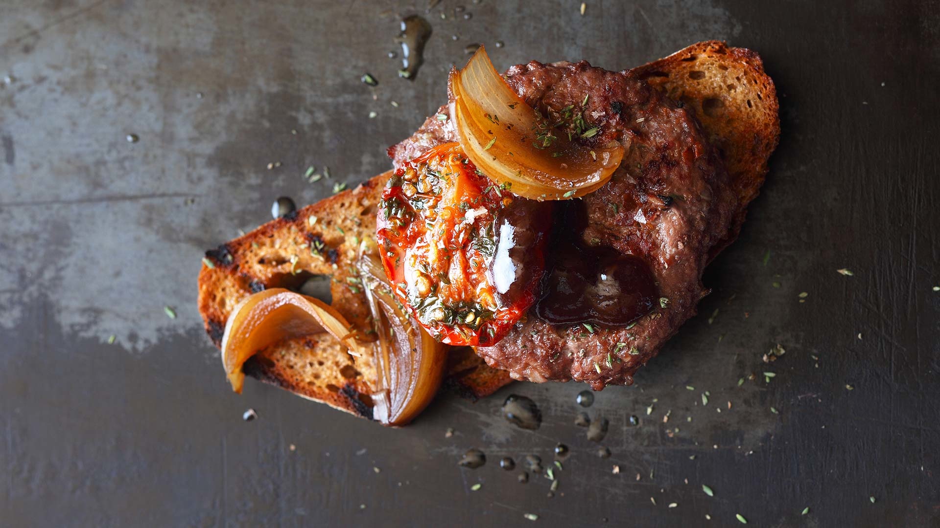  Saftiger Beef-Burger mit aromatischen Dörrtomaten auf dem Röstbrot mit süßen Zwiebeln und BBQ-Sauce


