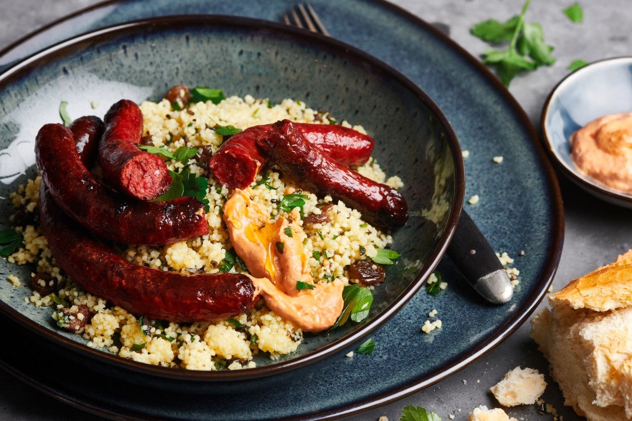  Gegrillte Merguez mit Harissa-Creme an Couscous, dazu Oliven und Petersilie

